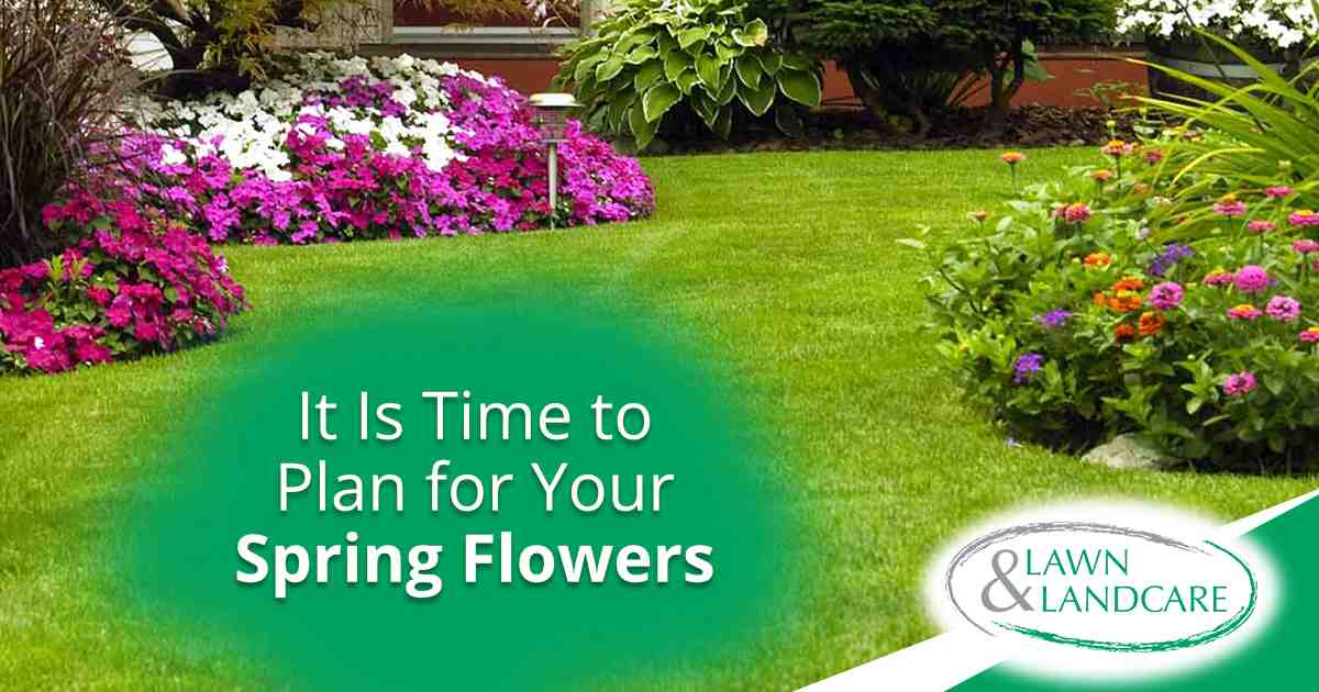 Green lawn surrounded by colorful pink, white, purple, and orange flower beds.